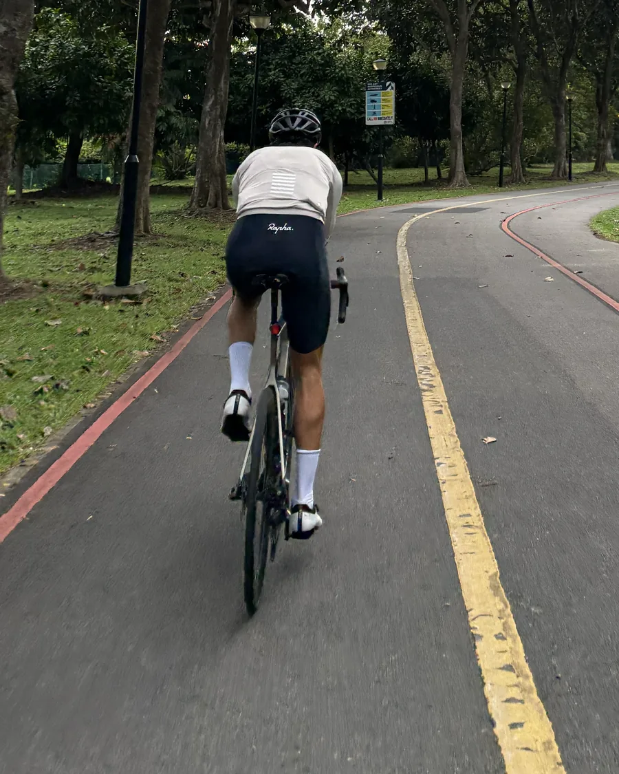 A lone rider heading out along a quiet tree-lined park path
